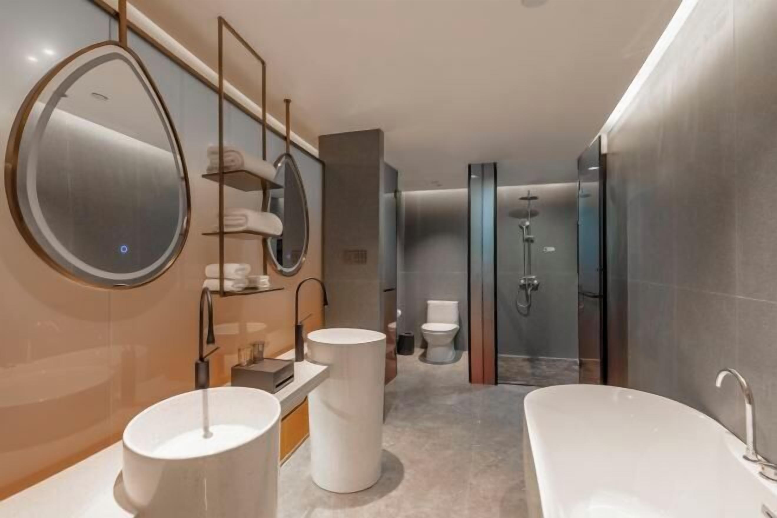 A modern bathroom with a large bathtub, two sinks, a toilet, and a shower area.