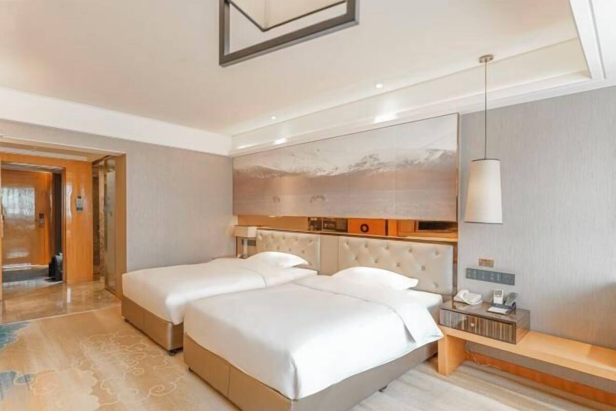 A hotel room with a large bed, a bedside table, a mirror, and a painting on the wall.