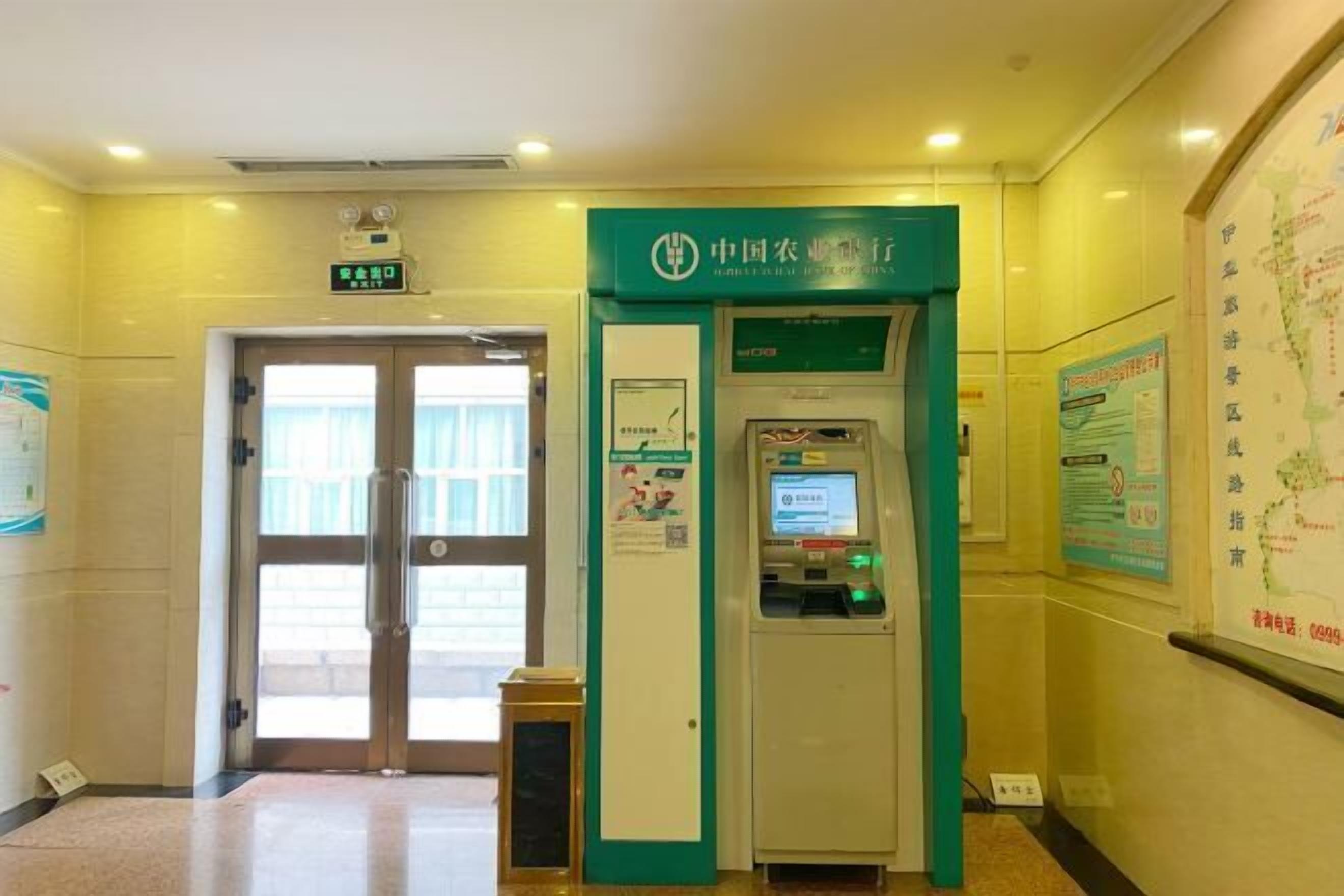 A reception area with a green sign, a digital information kiosk, and a door leading to another room.