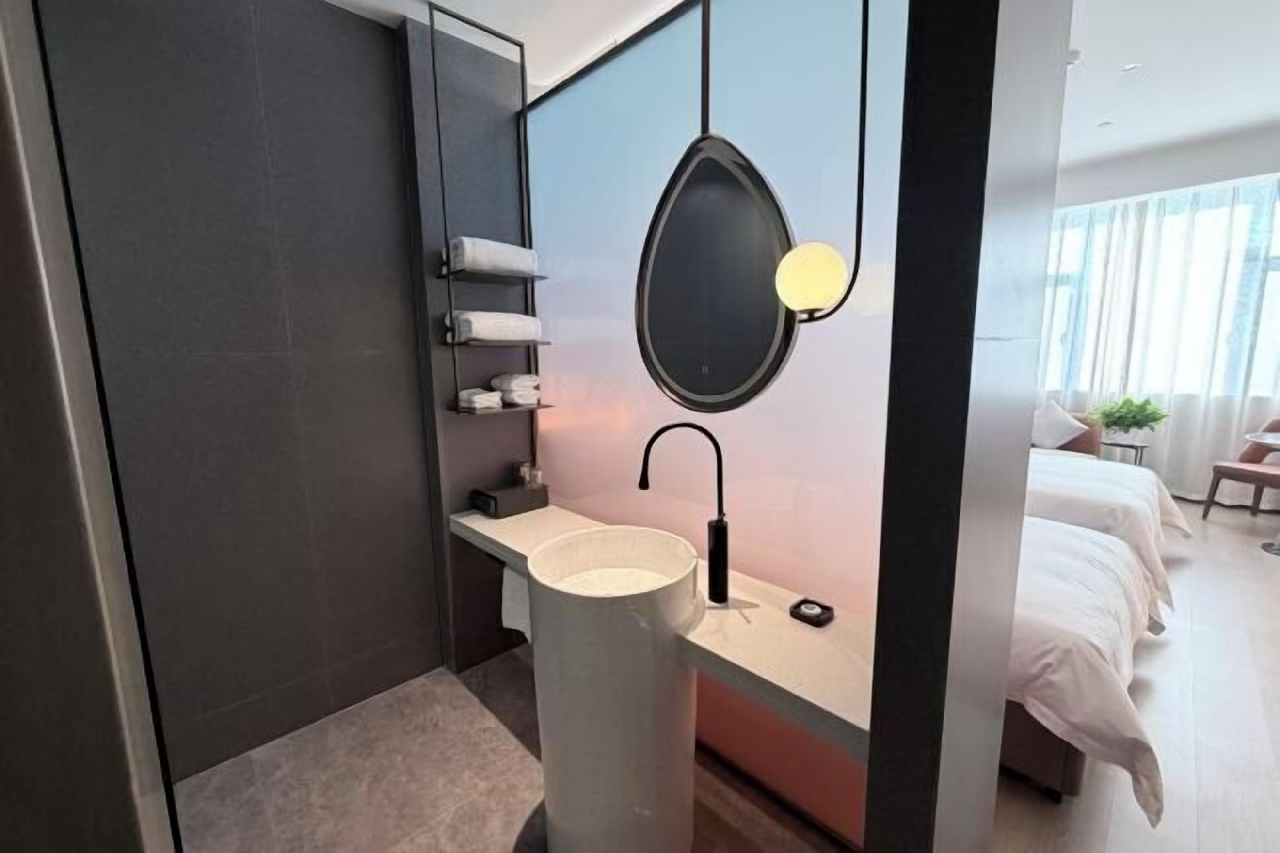A modern bathroom with a large sink, towel rack, and a mirror with a pendant light.