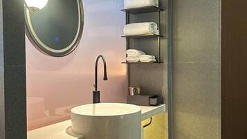 Un bagno moderno con uno specchio rotondo, un lavandino e scaffali con asciugamani piegati.