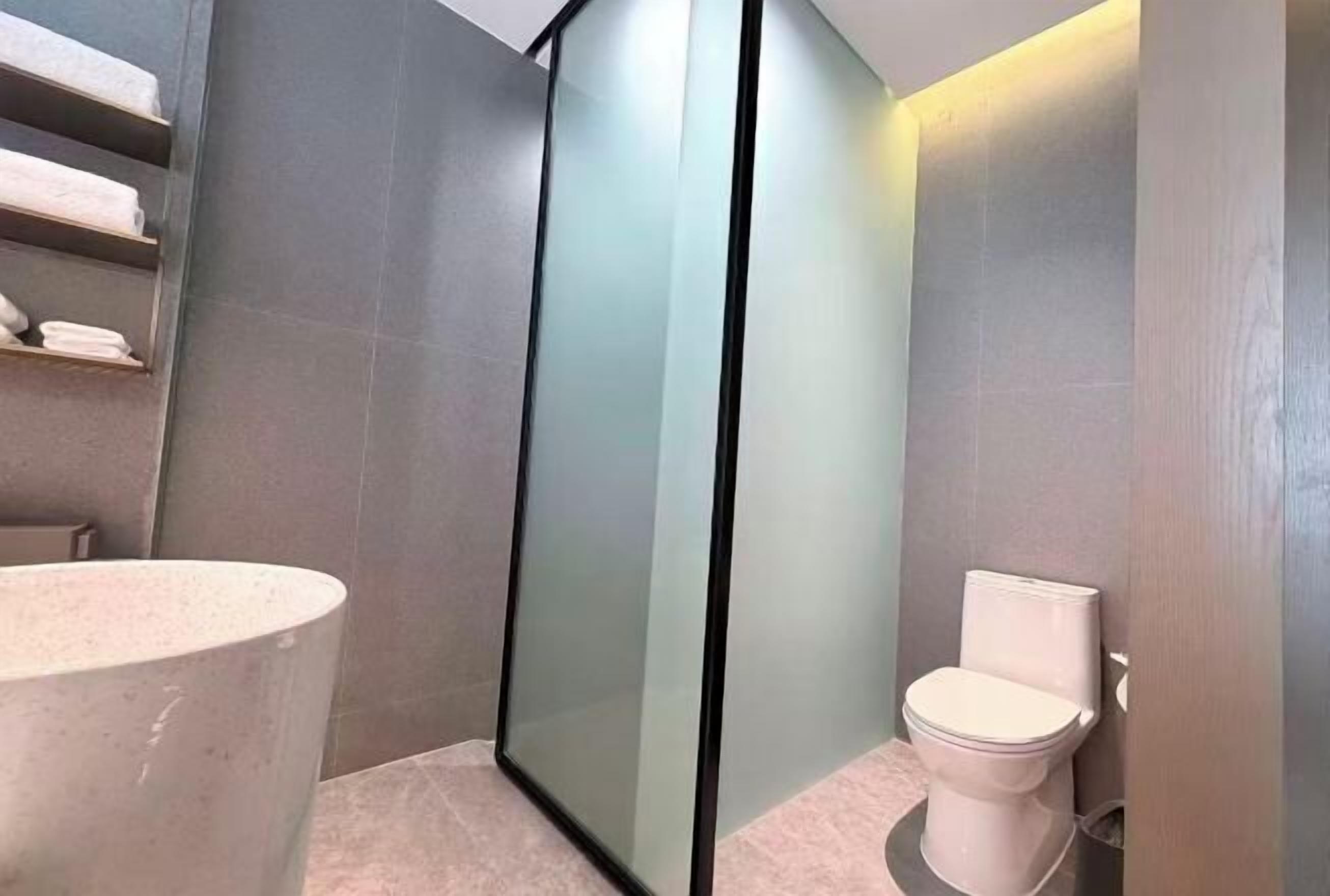 A modern bathroom with a glass partition, a toilet, and a sink.