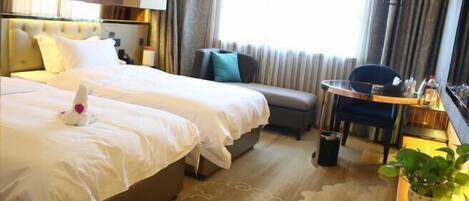 A hotel room with two beds, a sofa, a small table, and a potted plant.