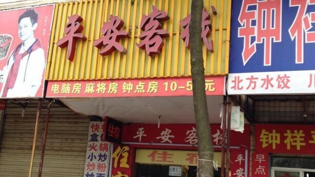 A building with multiple signs, including one for a hotel and another for a restaurant. - Pingan Inn (Jingmen)