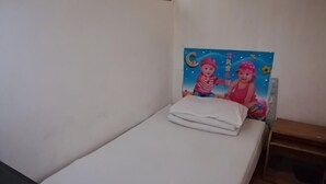 A small, single-bed room with a plain wall and a colorful painting above the bed. - Pingan Inn (Jingmen)