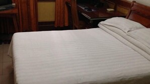 A hotel room with a bed, wooden headboard, a desk, and a chair. - Pingan Inn (Jingmen)