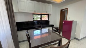 A compact kitchen with white cabinets, a black countertop, a stainless steel sink, and a red refrigerator. - Sonrisa - Golden Meadows by Hiverooms (Cordova)