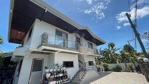 A two-story house with a balcony, a staircase, and a tiled patio area. - Sonrisa - Golden Meadows by Hiverooms (Cordova)
