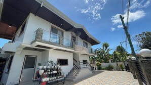 A two-story house with a balcony, a staircase, and a tiled patio area. - Sonrisa - Golden Meadows by Hiverooms (Cordova)