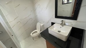 A bathroom with a white toilet, a white sink with a black countertop, and a mirror above the sink. - Sonrisa - Golden Meadows by Hiverooms (Cordova)
