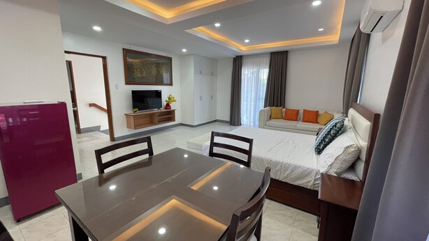 A modern hotel room with a dining area, a sofa, a TV, and a minibar. - Sonrisa - Golden Meadows by Hiverooms (Cordova)