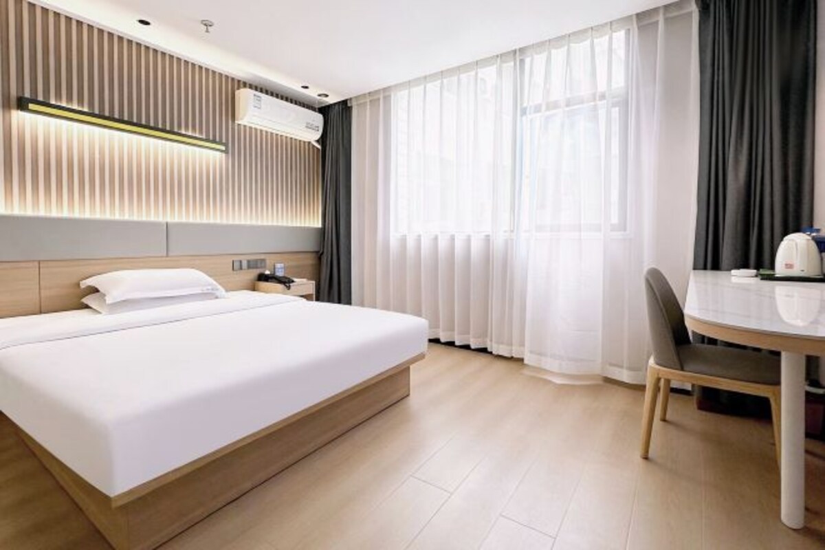 Quarto de hotel com cama, mesa de cabeceira, cadeira e mesa de jantar com uma cadeira.