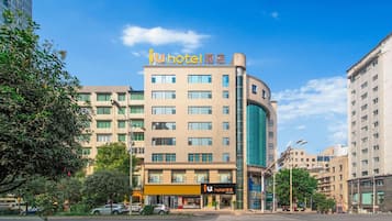 Un hotel con varios pisos, una llamativa sección de vidrio curvo y cielo despejado.
