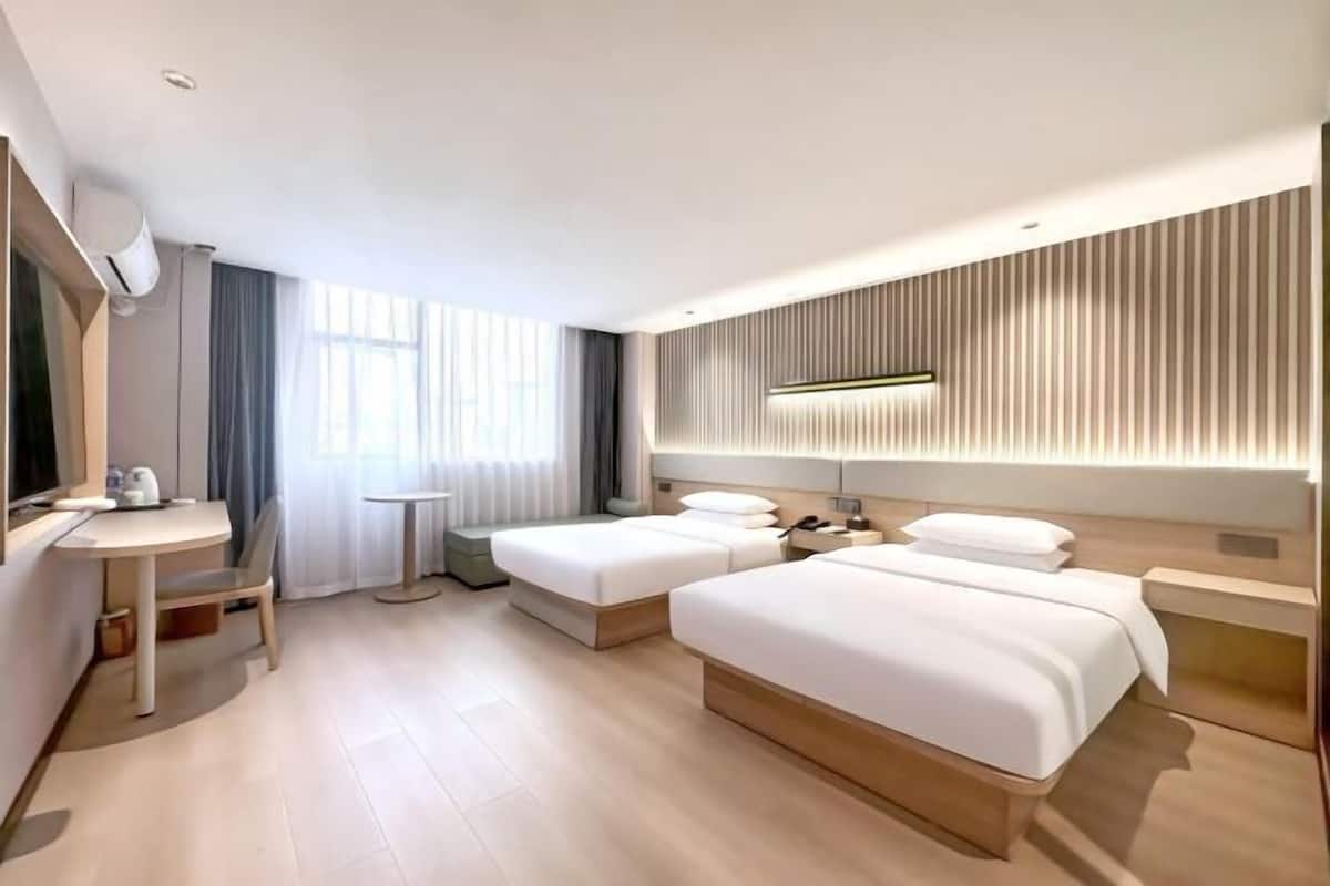 A hotel room with two beds, a desk, and a small table.
