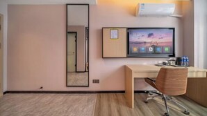A hotel room with a wooden desk, a large mirror, a flat-screen TV, and an air conditioning unit. - IU Hotel (Chongqing Fengdu Ghost City) (Fengdu County)