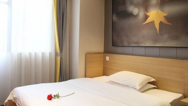 A hotel room with a bed, a large window with curtains, and a wall-mounted artwork of a star. - IU Hotel (Fengdu County)