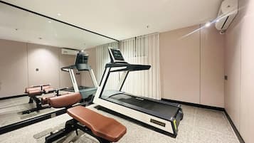 Un gimnasio moderno con cinta de correr, banco y máquinas de pesas.
