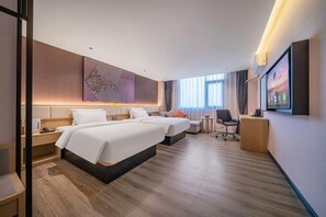 Quarto de hotel com duas camas, escrivaninha, cadeira, televisão e uma janela grande.