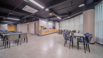 Una amplia sala de conferencias con una larga mesa y sillas, un área de recepción con mostrador, y un ventanal con cortinas.