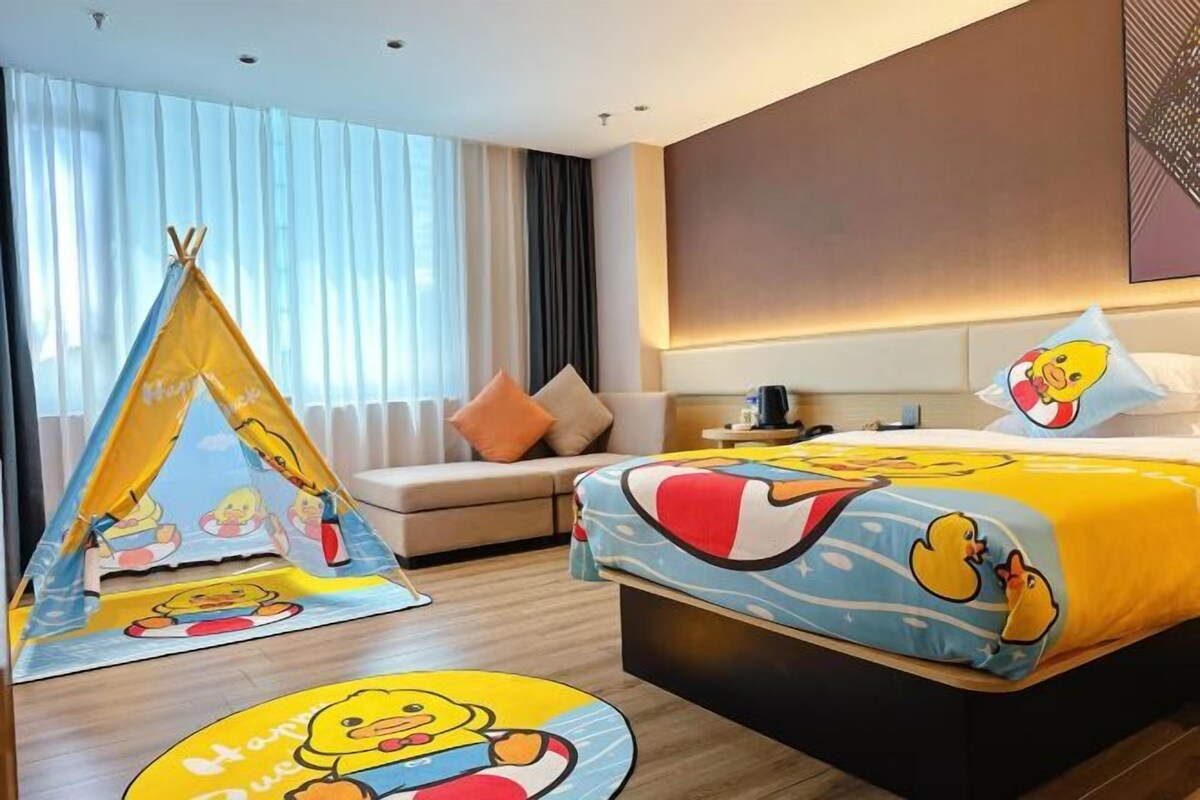 Quarto de hotel com cama, sofá, uma tenda e uma janela grande com cortinas.