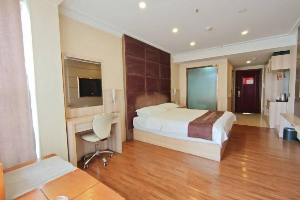 A hotel room with a bed, desk, chair, and a television.