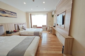 Habitación de hotel con dos camas, un escritorio y vistas al exterior.