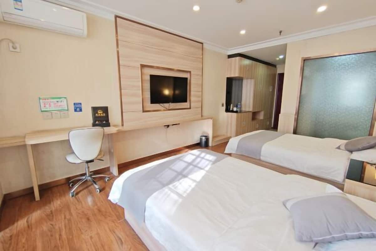 A hotel room with two beds, a desk, and a TV.