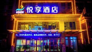 A hotel with a neon sign and a glass entrance.