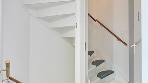 Un escalier avec des rampes en bois et des marches recouvertes d’une moquette verte.