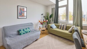 Un salon avec deux canapés, une petite table et une grande fenêtre avec des rideaux.