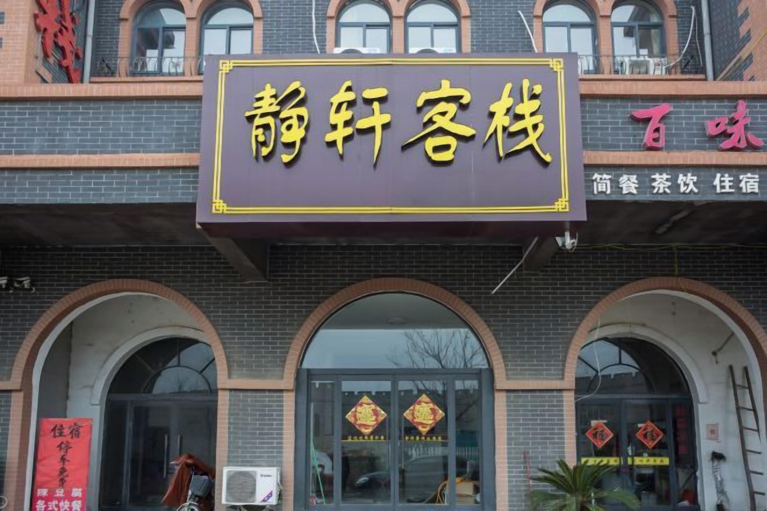 A building with a sign that reads '静轩客栈' and another sign with '百味' indicating a restaurant.