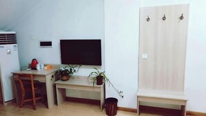 A small room with a desk, chair, TV, and wardrobe. - Zaozhuang Jingxuan Inn (Zaozhuang)