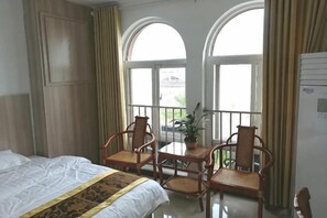 Ein Hotelzimmer mit einem Bett, zwei Stühlen, einem kleinen Tisch und einer Topfpflanze.