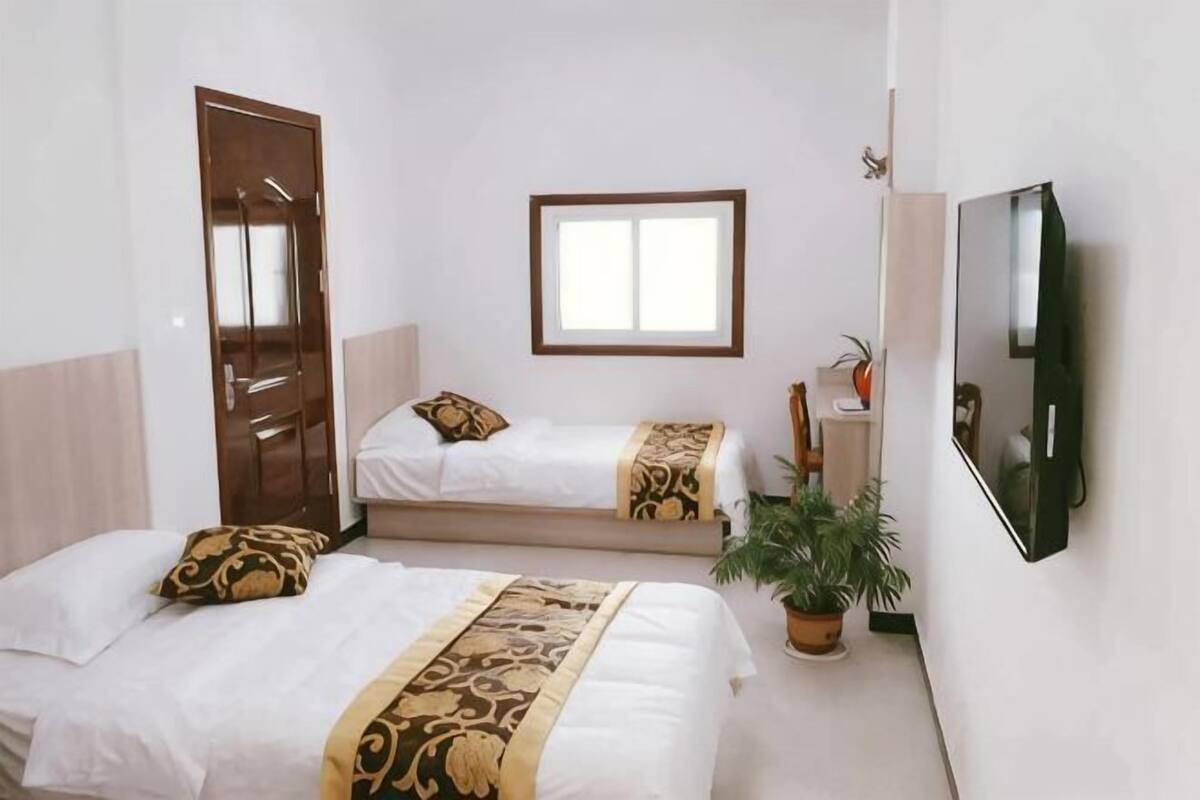 A room with two beds, a window, a door, and a mirror.