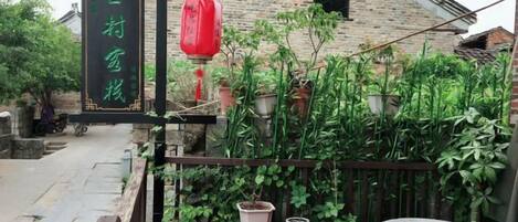 Un edificio tradicional con un letrero, plantas en macetas y una mesa de madera.