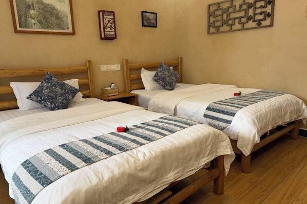Dos camas individuales con estructura de madera, ropa de cama blanca y almohadas decorativas.