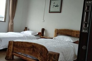 A room with two wooden beds, a nightstand, a framed picture on the wall, and a window with curtains. - Yongzhou Ancient Village Inn (Jiangyong)