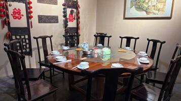 A round dining table with chairs, set with plates, bowls, and a teapot.