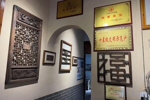 Un pasillo con marcos de certificados en las paredes, una ventana de madera con celosía tradicional y un piso de baldosas.