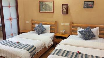Une chambre avec deux lits, des têtes de lit en bois et une table de chevet en bois avec un téléphone.