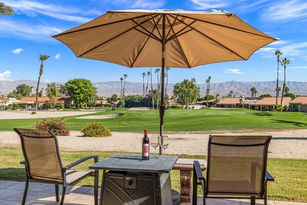 Une terrasse extérieure avec une table, des chaises et un grand parasol.