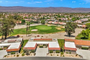 Un parcours de golf doté d’un green d’entraînement, entouré de bâtiments résidentiels aux toits recouverts de tuiles rouges.