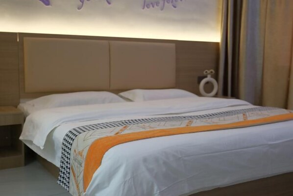 A hotel room with a bed, a nightstand, and a wall-mounted lamp.