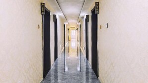 A long, narrow hallway with marble flooring and walls, featuring doors with numbers and a central light source. - Xiwuqi Jindi Hotel (West Ujimqin Banner)