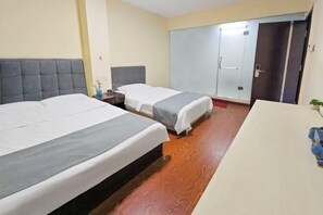 Habitación de hotel con dos camas, suelo de madera, escritorio y armario.