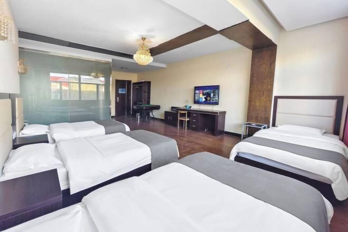 A hotel room with multiple beds, a desk, and a television.