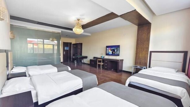 Una habitación de hotel con varias camas, un escritorio y un televisor.