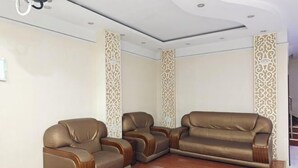 Un rincón amoblado con tres sofás de cuero marrón y paneles blancos decorativos en las paredes.