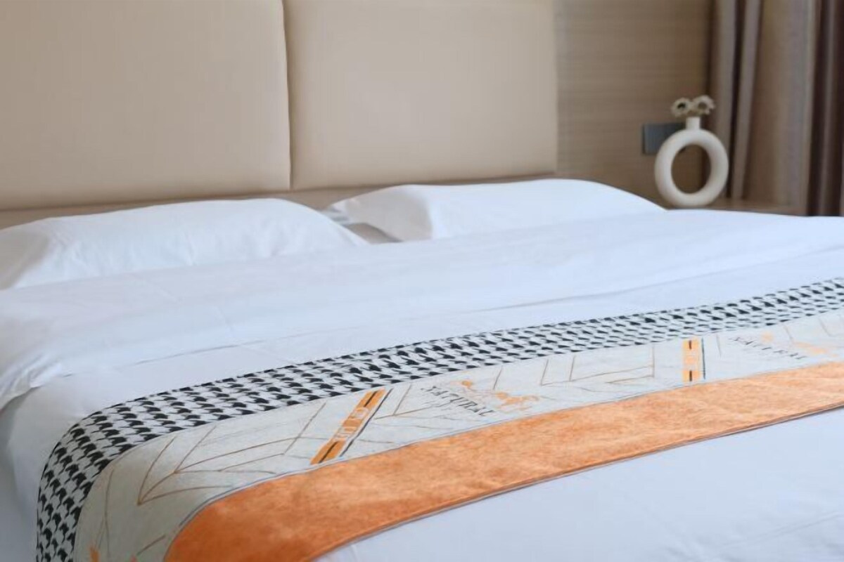 A neatly made bed with a patterned bedspread and a headboard.