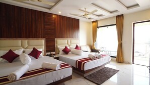 A hotel room with two beds, wooden paneling on the walls, ceiling fans, and a large window with curtains. - Lipi Resort and Spa (Kanthi)